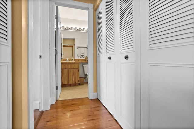 hallway with light wood-style floors and a sink