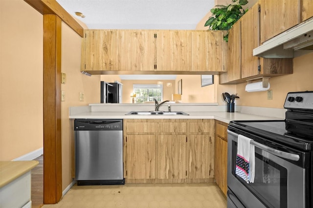 kitchen featuring light floors, a sink, stainless steel appliances, light countertops, and under cabinet range hood