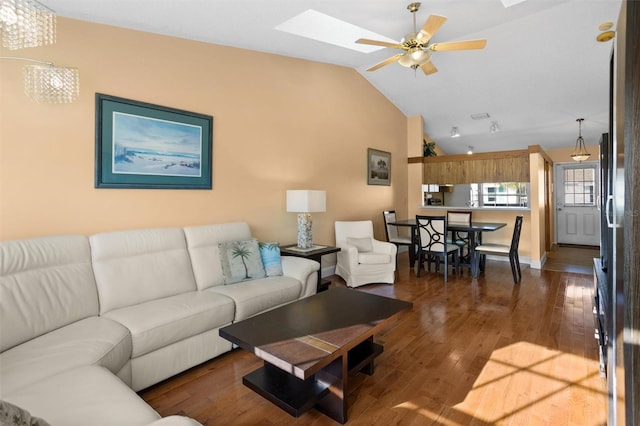 living room featuring vaulted ceiling with skylight, a ceiling fan, and hardwood / wood-style flooring