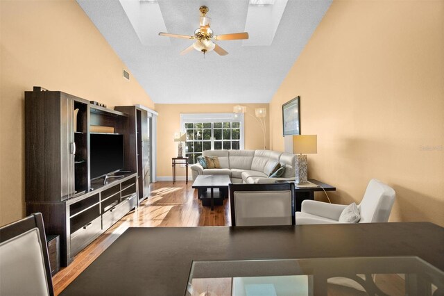 living room featuring visible vents, baseboards, lofted ceiling, wood finished floors, and a ceiling fan