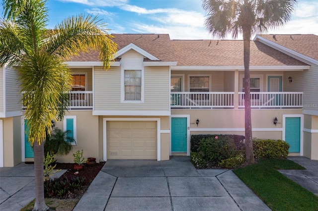 townhome / multi-family property featuring roof with shingles, a garage, driveway, and stucco siding