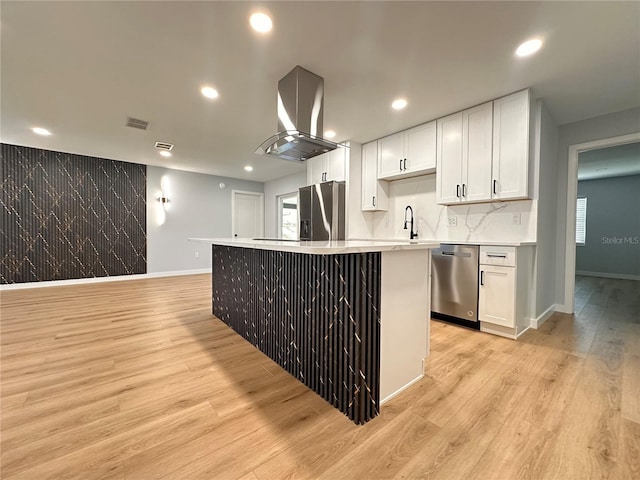 kitchen featuring white cabinets, extractor fan, stainless steel appliances, light wood-style floors, and a sink