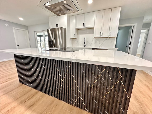 kitchen with light wood-type flooring, black electric stovetop, stainless steel fridge with ice dispenser, and exhaust hood