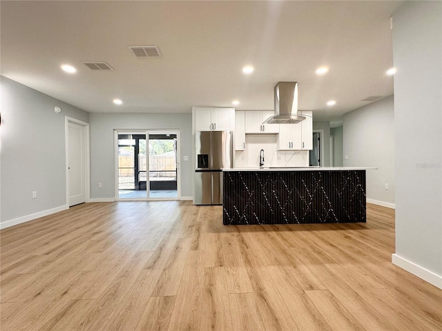 kitchen featuring white cabinets, island exhaust hood, visible vents, and stainless steel refrigerator with ice dispenser