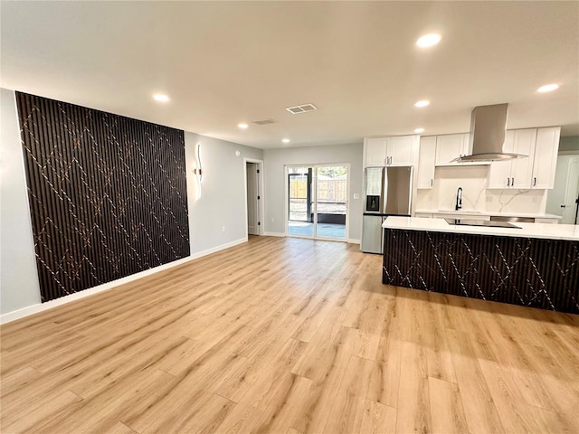 kitchen featuring light countertops, visible vents, white cabinets, stainless steel fridge, and exhaust hood