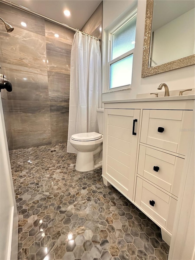 full bathroom featuring toilet, tiled shower, and vanity