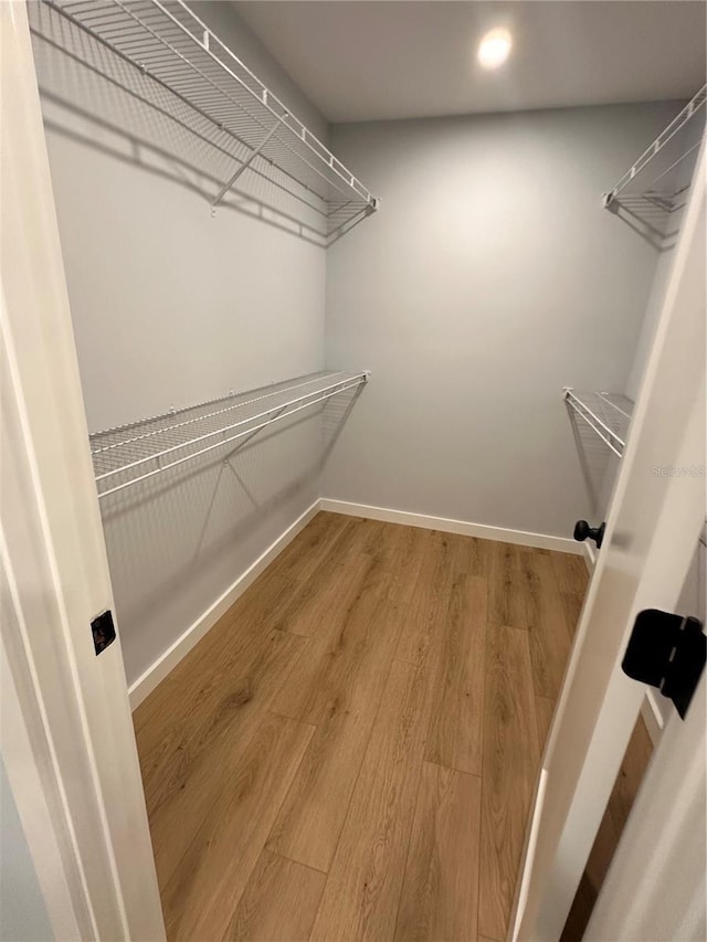 walk in closet with wood finished floors