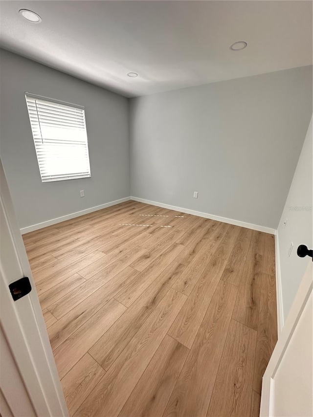 empty room featuring light wood finished floors, baseboards, and recessed lighting