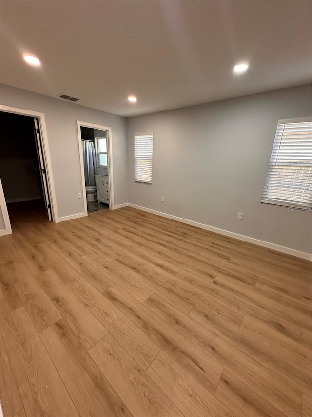 unfurnished bedroom featuring baseboards, visible vents, a spacious closet, light wood-style floors, and recessed lighting