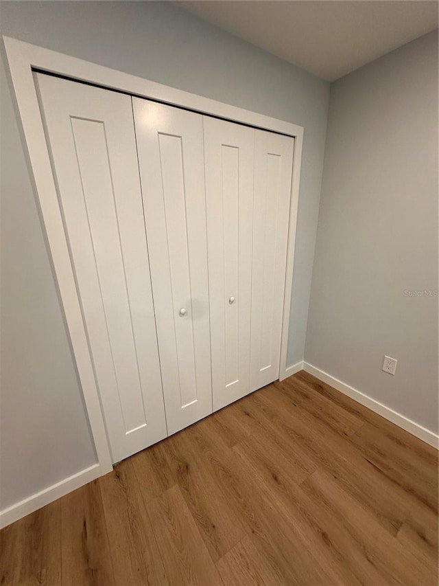 unfurnished bedroom featuring a closet, light wood-type flooring, and baseboards