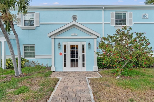 doorway to property featuring a yard and stucco siding