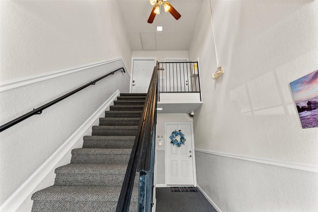 staircase featuring ceiling fan and a textured wall