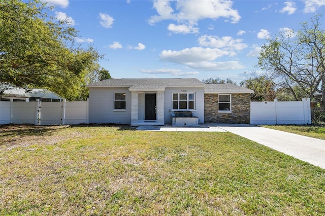 ranch-style home featuring stone siding, a front yard, fence, and a gate