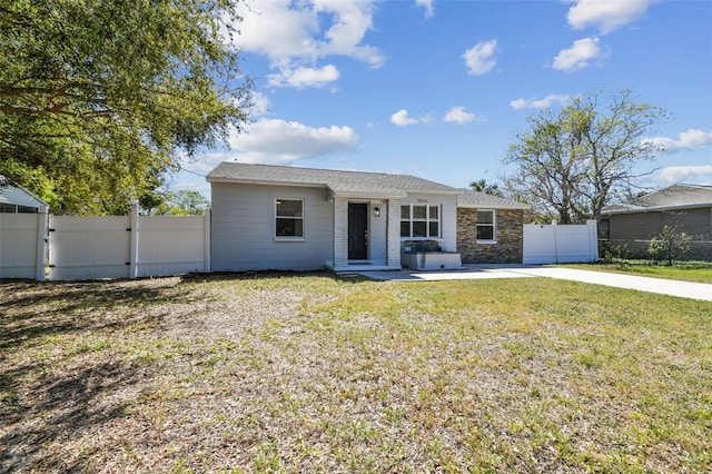 ranch-style house with concrete driveway, stone siding, a gate, fence, and a front lawn