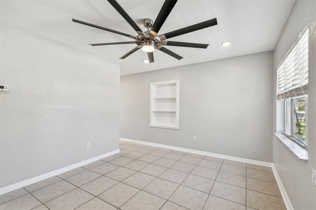 spare room with built in shelves, baseboards, and a ceiling fan