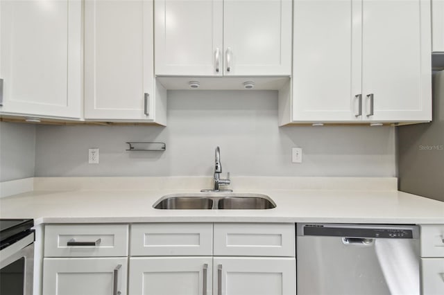 kitchen featuring stainless steel appliances, a sink, light countertops, and white cabinetry