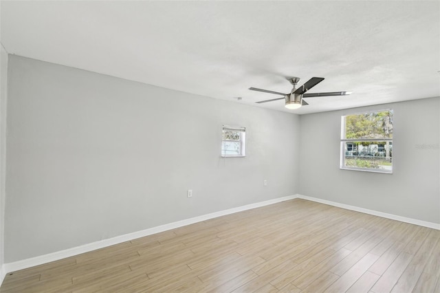 empty room featuring a ceiling fan, plenty of natural light, light wood-style flooring, and baseboards