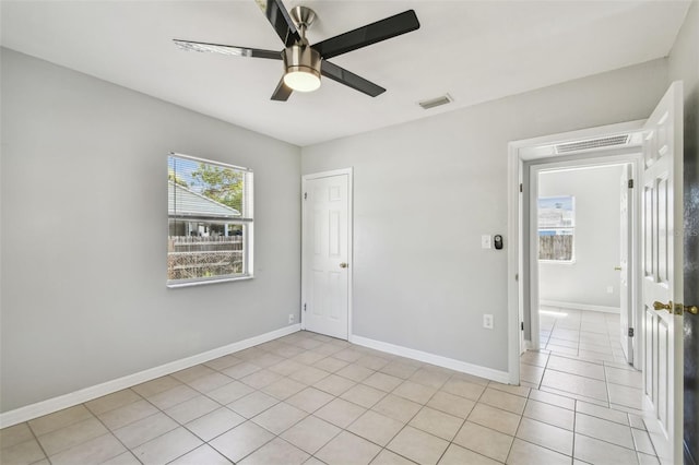 empty room with light tile patterned floors, baseboards, visible vents, and ceiling fan