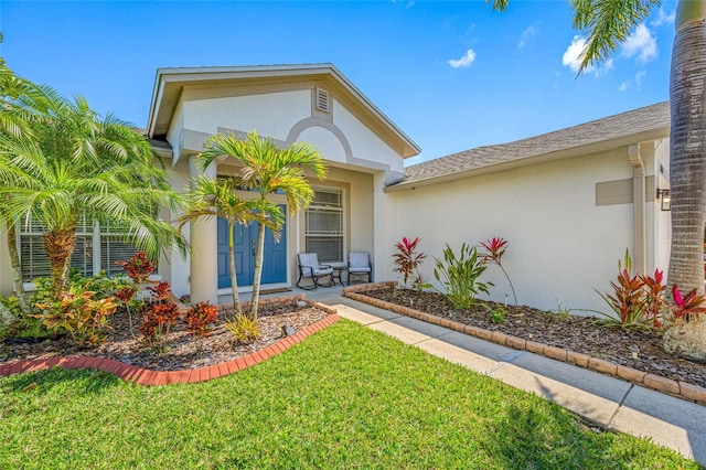 entrance to property featuring a yard, covered porch, and stucco siding