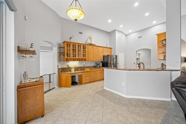 kitchen featuring glass insert cabinets, arched walkways, stainless steel fridge with ice dispenser, and open shelves