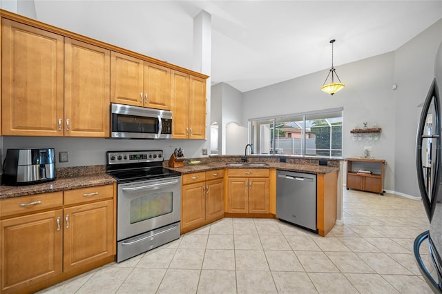 kitchen featuring stainless steel appliances, brown cabinetry, a peninsula, and a sink