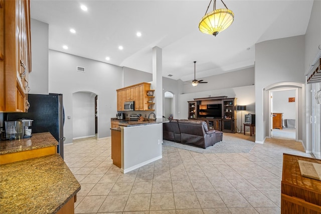 kitchen featuring arched walkways, high vaulted ceiling, a ceiling fan, open floor plan, and appliances with stainless steel finishes