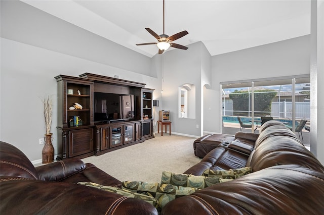 living area with baseboards, high vaulted ceiling, ceiling fan, and carpet flooring