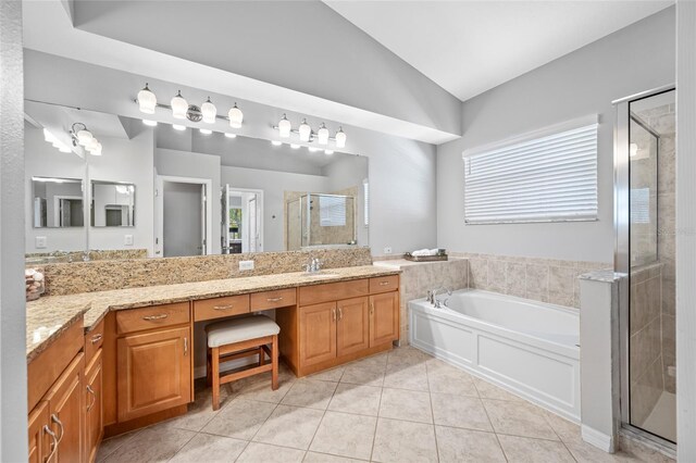 bathroom featuring vanity, vaulted ceiling, a shower stall, a bath, and tile patterned floors