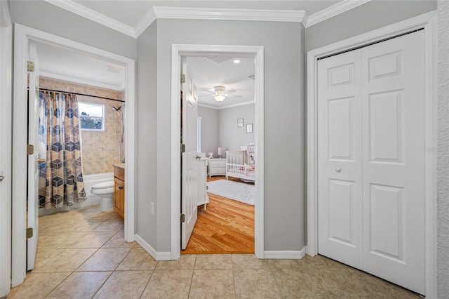 hall featuring baseboards, ornamental molding, and light tile patterned flooring