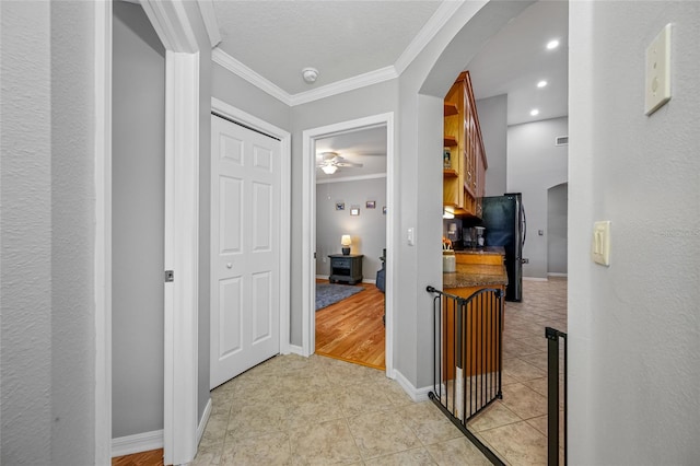 hallway featuring arched walkways, crown molding, light tile patterned floors, recessed lighting, and baseboards