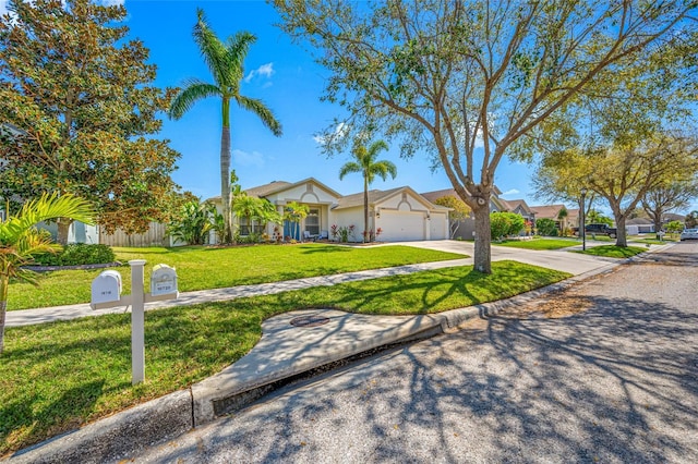 view of front of property with an attached garage, driveway, a front lawn, and fence