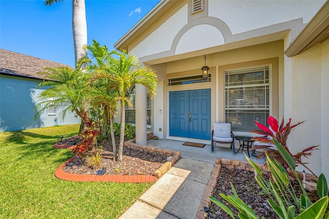 entrance to property featuring a porch, a lawn, and stucco siding