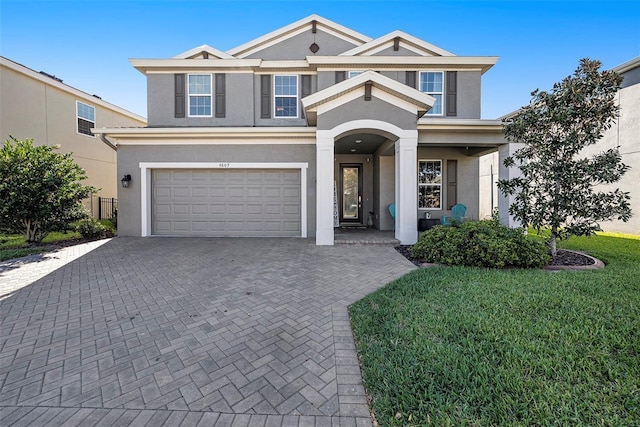 view of front of property featuring a garage, decorative driveway, a front yard, and stucco siding