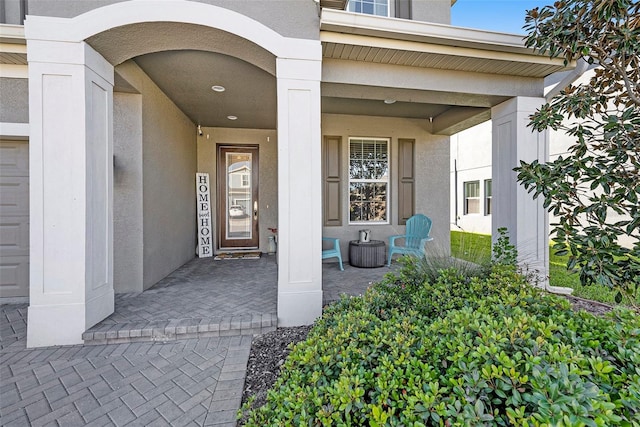 entrance to property with covered porch and stucco siding