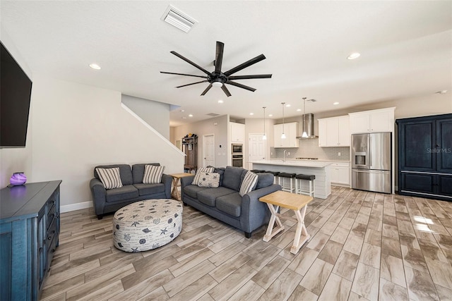 living area with recessed lighting, visible vents, a ceiling fan, light wood-type flooring, and baseboards