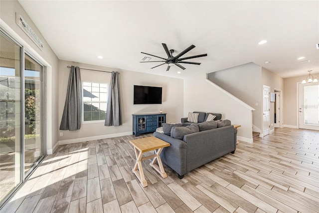 living area featuring ceiling fan with notable chandelier, wood finish floors, baseboards, and recessed lighting