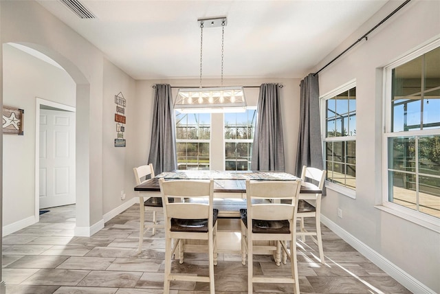 dining area featuring baseboards, visible vents, arched walkways, and wood finish floors