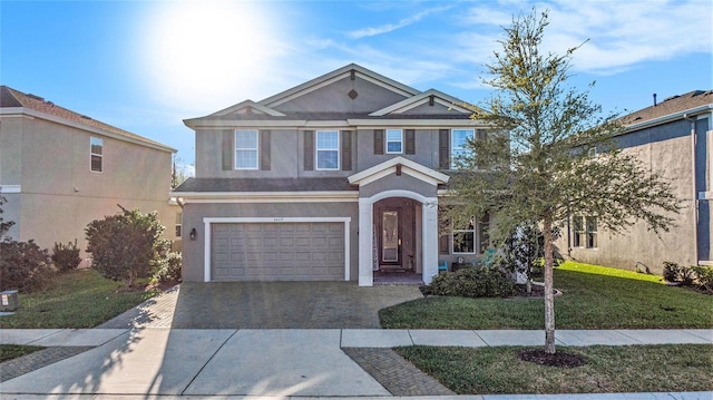 view of front facade with a garage, a front lawn, decorative driveway, and stucco siding