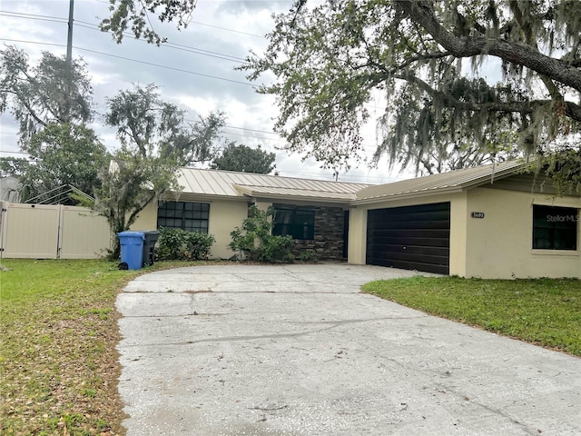 view of front facade with metal roof, concrete driveway, a garage, and stucco siding