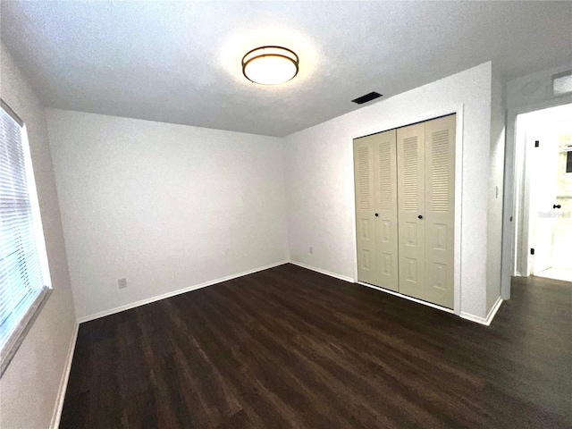 unfurnished bedroom with baseboards, a closet, visible vents, and wood finished floors