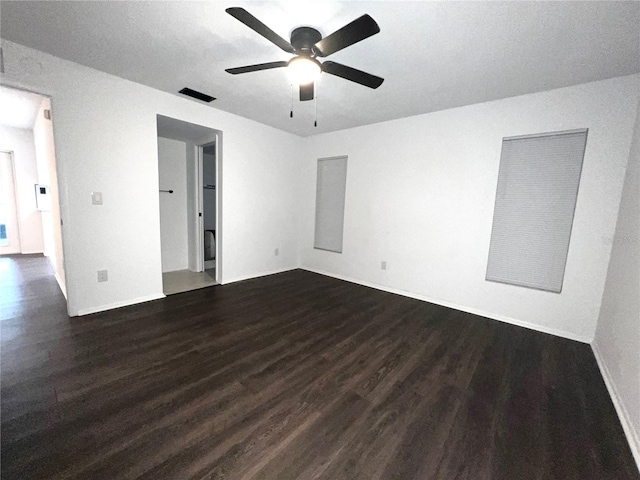 empty room with ceiling fan, dark wood finished floors, visible vents, and baseboards