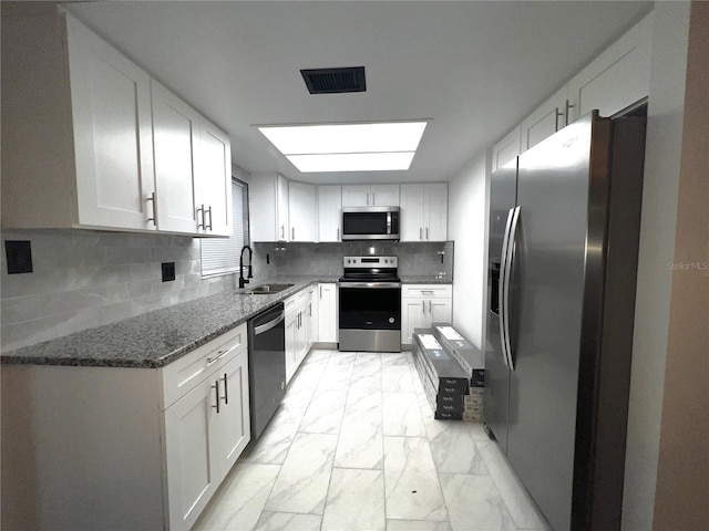 kitchen featuring marble finish floor, visible vents, appliances with stainless steel finishes, a sink, and dark stone countertops