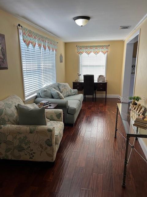 living room featuring baseboards, visible vents, and dark wood-type flooring