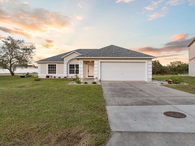 ranch-style home with stucco siding, a shingled roof, a garage, driveway, and a front lawn