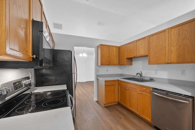 kitchen with stainless steel appliances, light countertops, visible vents, a sink, and wood finished floors