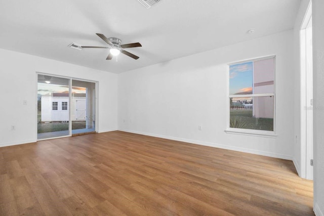 interior space featuring baseboards, wood finished floors, a ceiling fan, and access to exterior