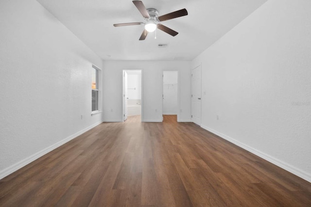 unfurnished bedroom featuring visible vents, a spacious closet, baseboards, and wood finished floors