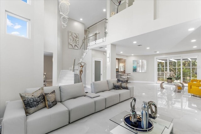 living area featuring recessed lighting, a healthy amount of sunlight, stairs, and a towering ceiling