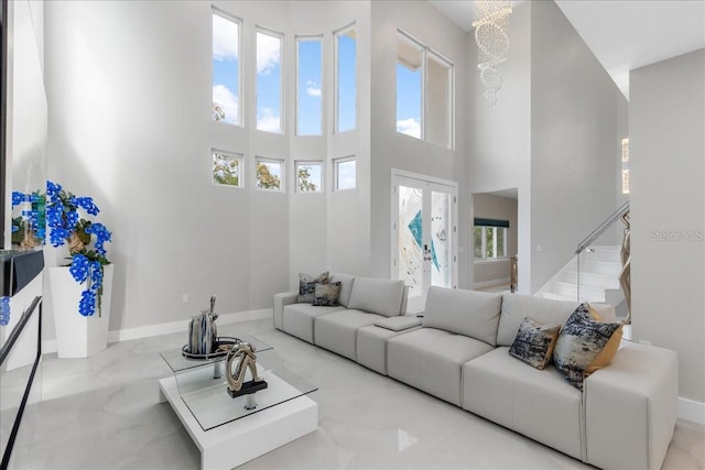 living area featuring stairway, baseboards, marble finish floor, and a towering ceiling