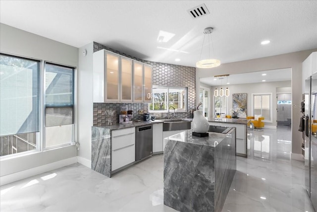 kitchen with visible vents, modern cabinets, a sink, stainless steel dishwasher, and a center island